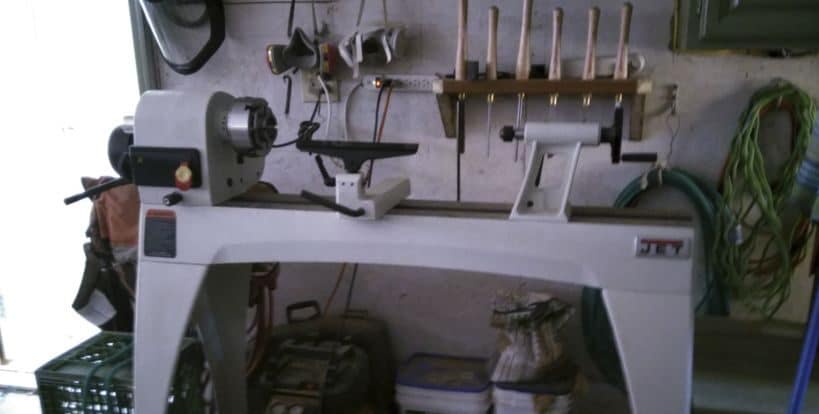 "Faceplate and chisels hanging on the wall including a white wood lathe standing on the floor"