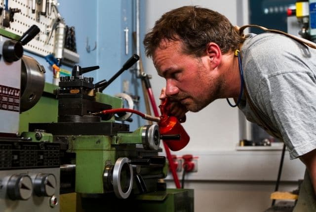 "A metalworker checking his lathe machine closely"