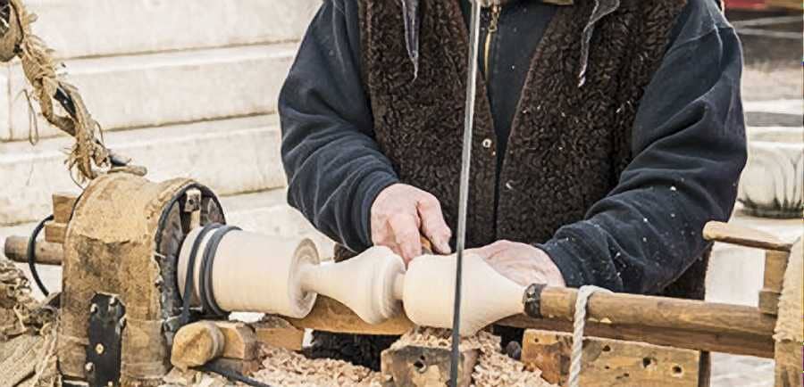 "man is working with a wood lathe machine"