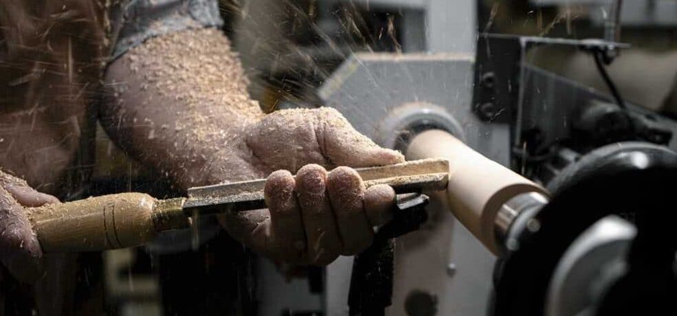 "a beginner woodturner turning spindle on a wood lathe with a chisel"