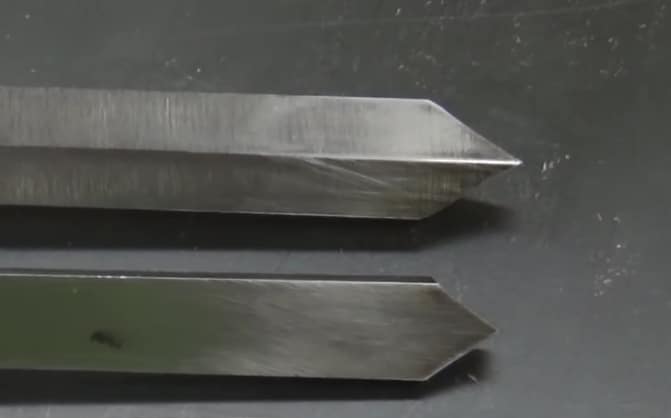 "The edges of two parting tools blade lying on a black surface"