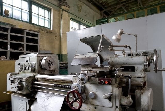 "an old metal working lathe machine inside a workshop"