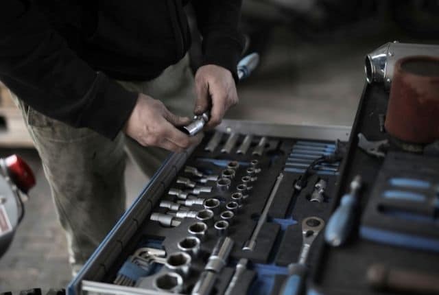 "man's hand holding a tool out of his tool box"