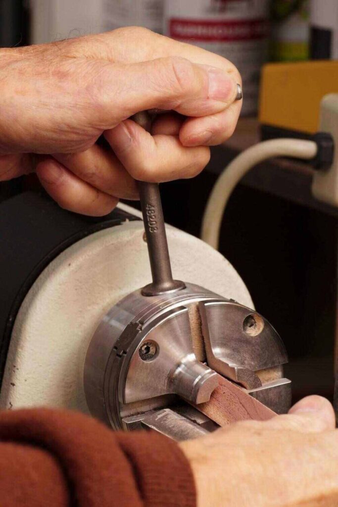 "woodturner tightening his wood lathe chuck with a key"