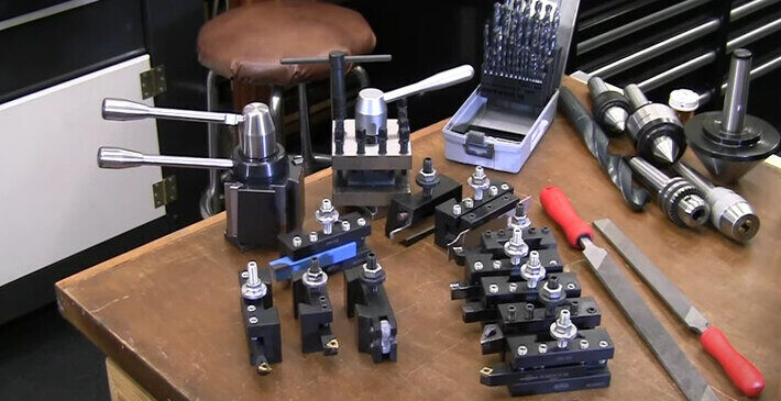 A table full of quick change tool posts, cutting tools and few other metal lathe tools"