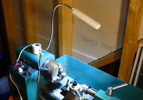 "a gooseneck led lights mounted on a blue colored metal lathe machine"