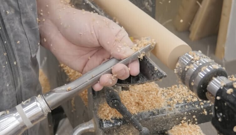 "a man turning a wood with a spindle roughing gouge"